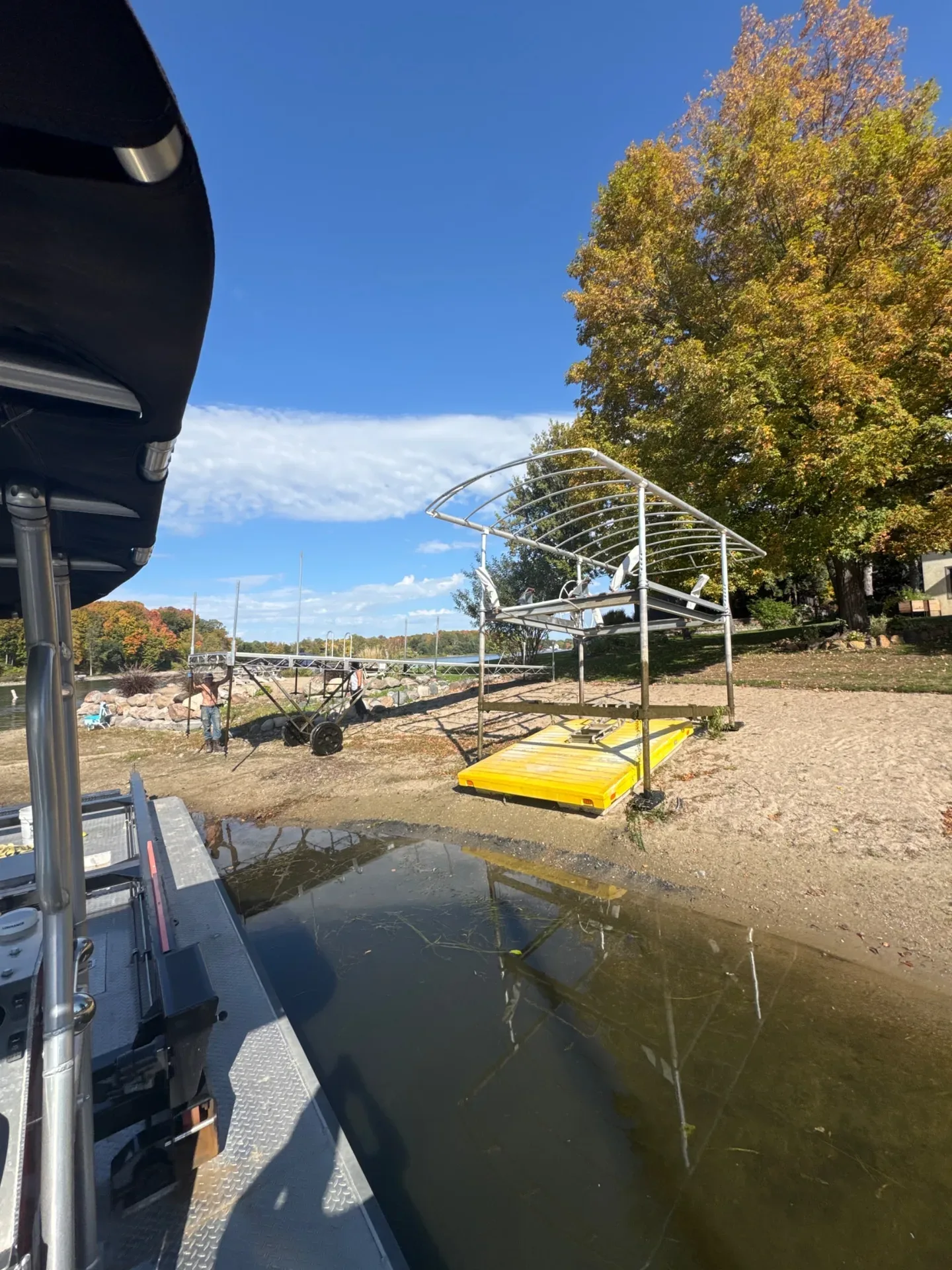 Boat lift and canopy frame set on the beach beside the BigWave Lake Service barge after fall removal on Prior Lake, October 2026